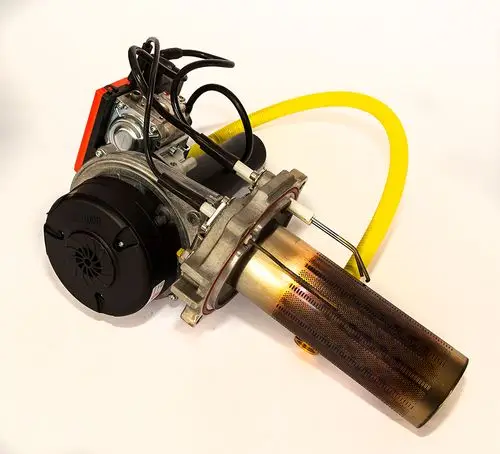 Brenner von Daikin mit einem zylindrischen Gehäuse, mehreren Anschlüssen und einem langen Auspuffrohr, das eine bearbeitete Metalloberfläche aufweist.